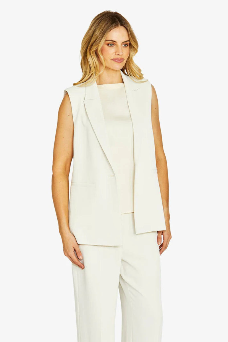 Woman wearing a white sleeveless blazer and pants on a white background