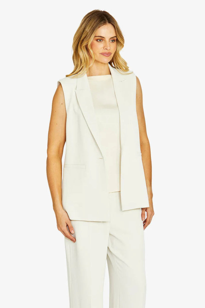Woman wearing a white sleeveless blazer and pants on a white background