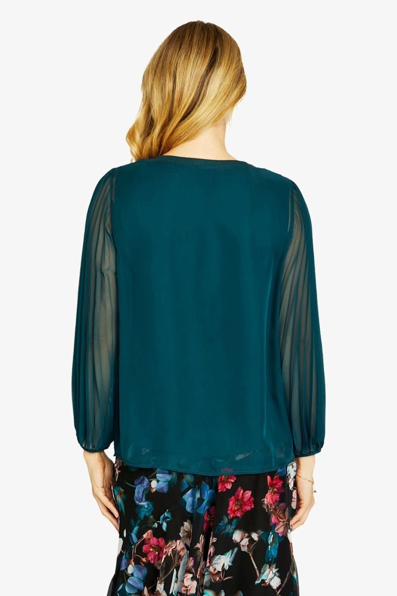 Green blouse with sheer sleeves worn by a person on a white background