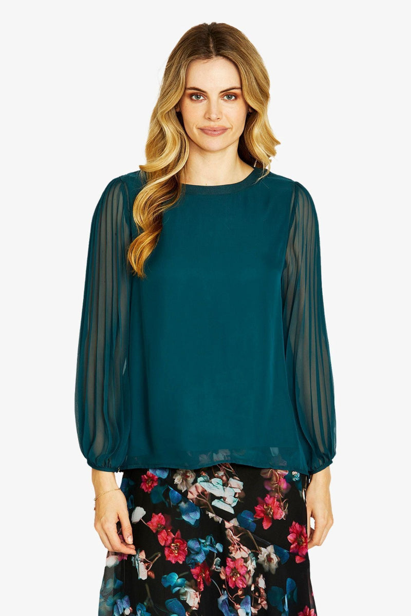 Green blouse with sheer sleeves worn by a person on a white background