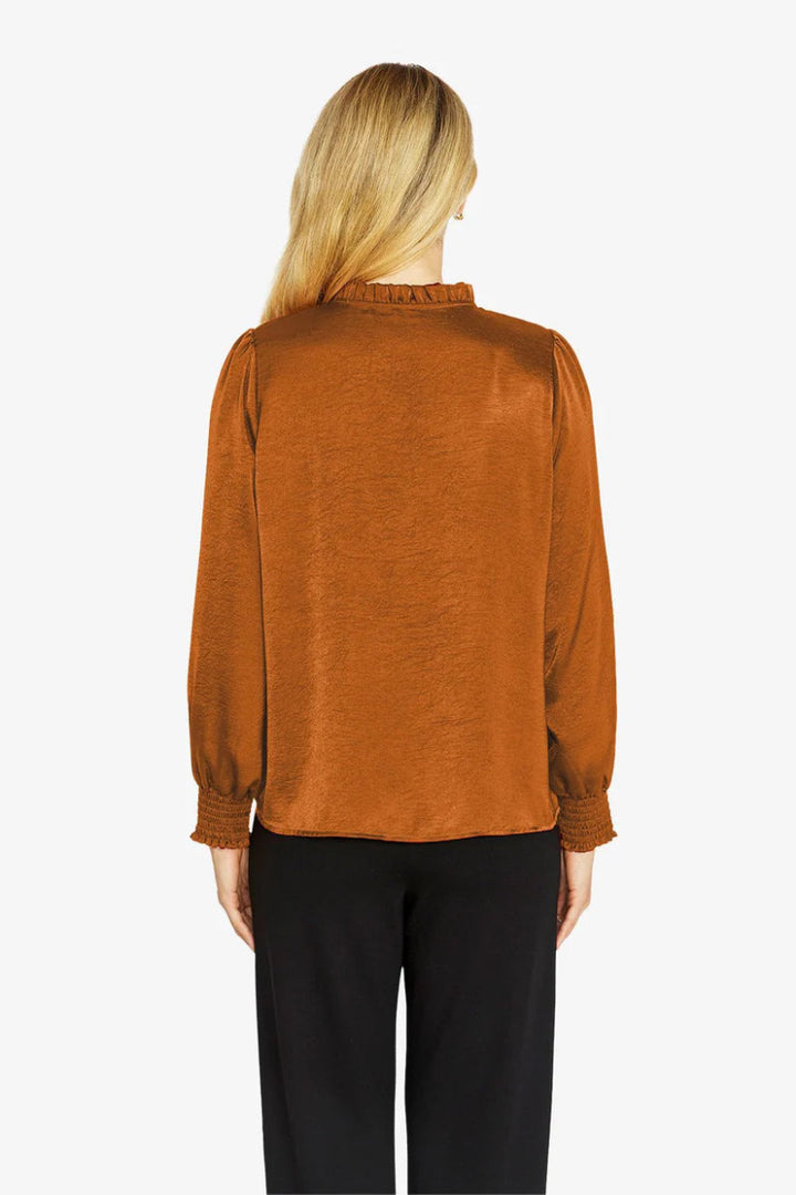 Person wearing a rust-colored blouse with long sleeves on a white background