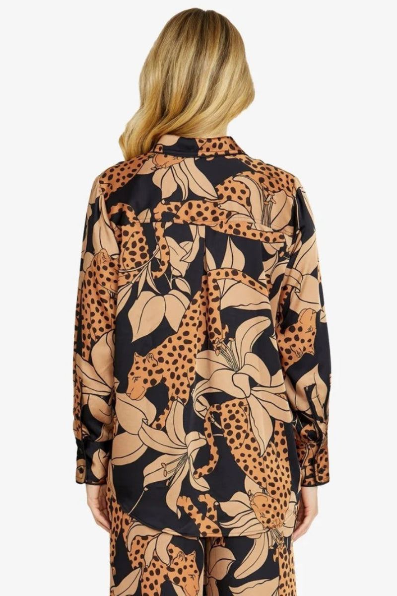 Person wearing a patterned shirt with animal and floral designs on a white background