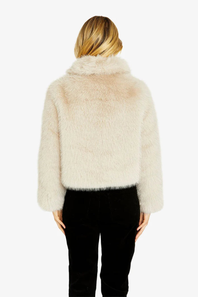 Person wearing a fluffy beige jacket on a white background