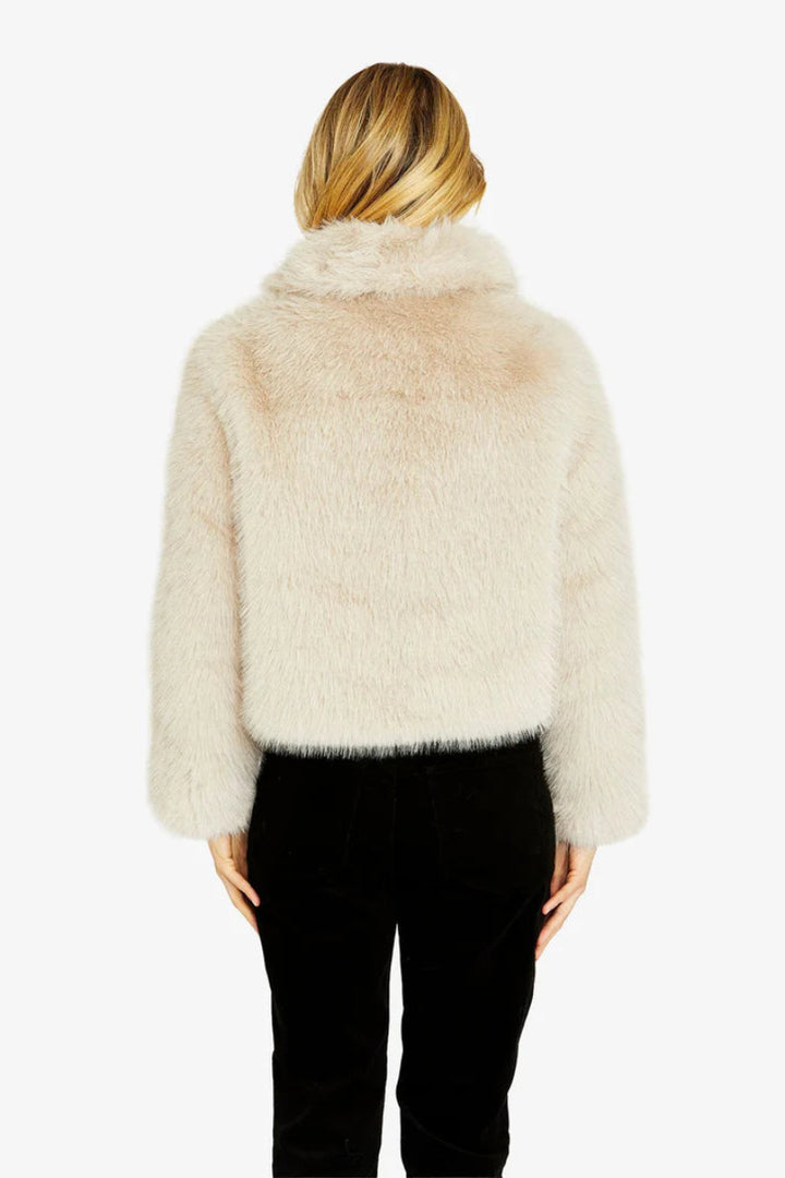 Person wearing a fluffy beige jacket on a white background