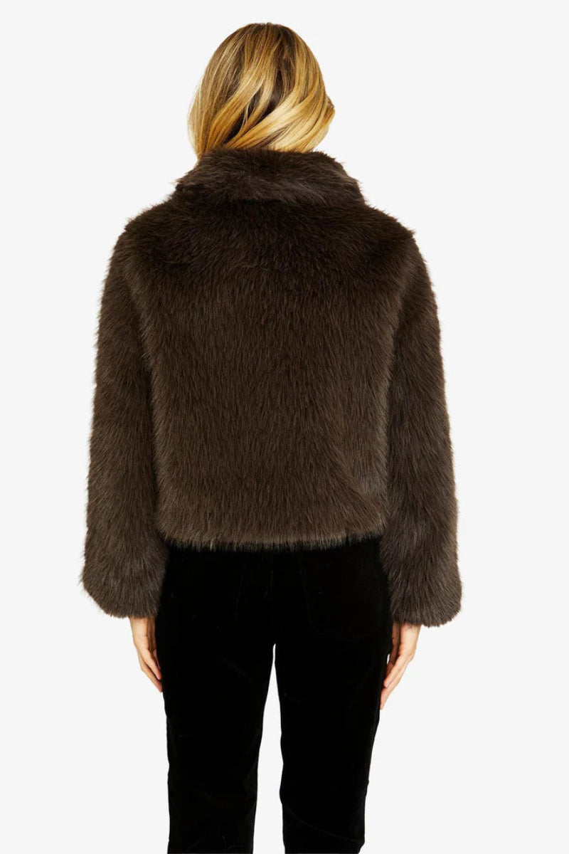 Brown fur jacket worn by a person on a white background