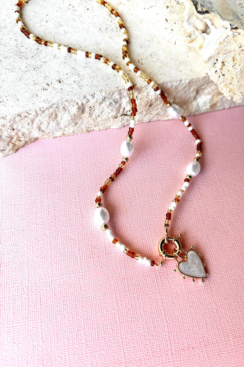 Necklace with heart charm on a pink fabric background