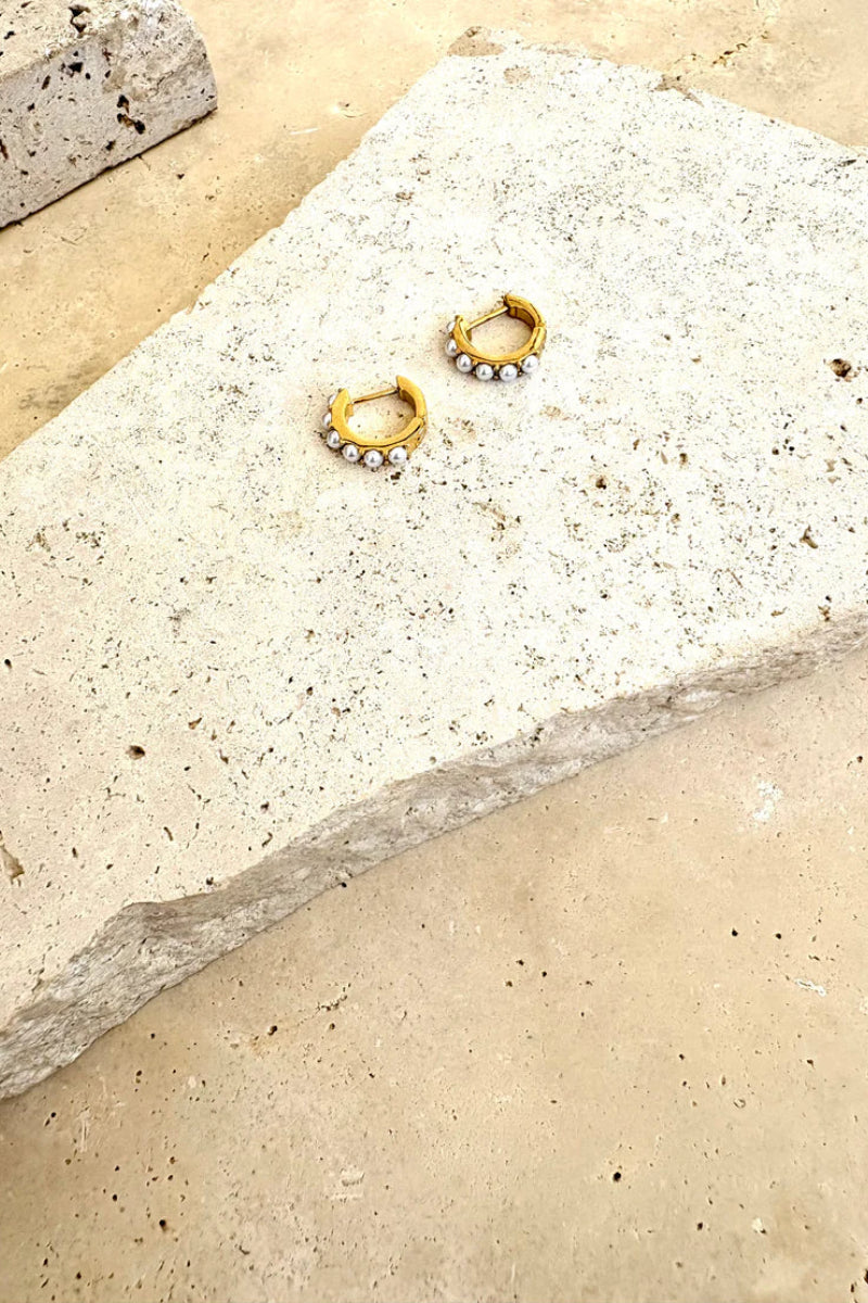 Gold hoop earrings on a textured stone surface