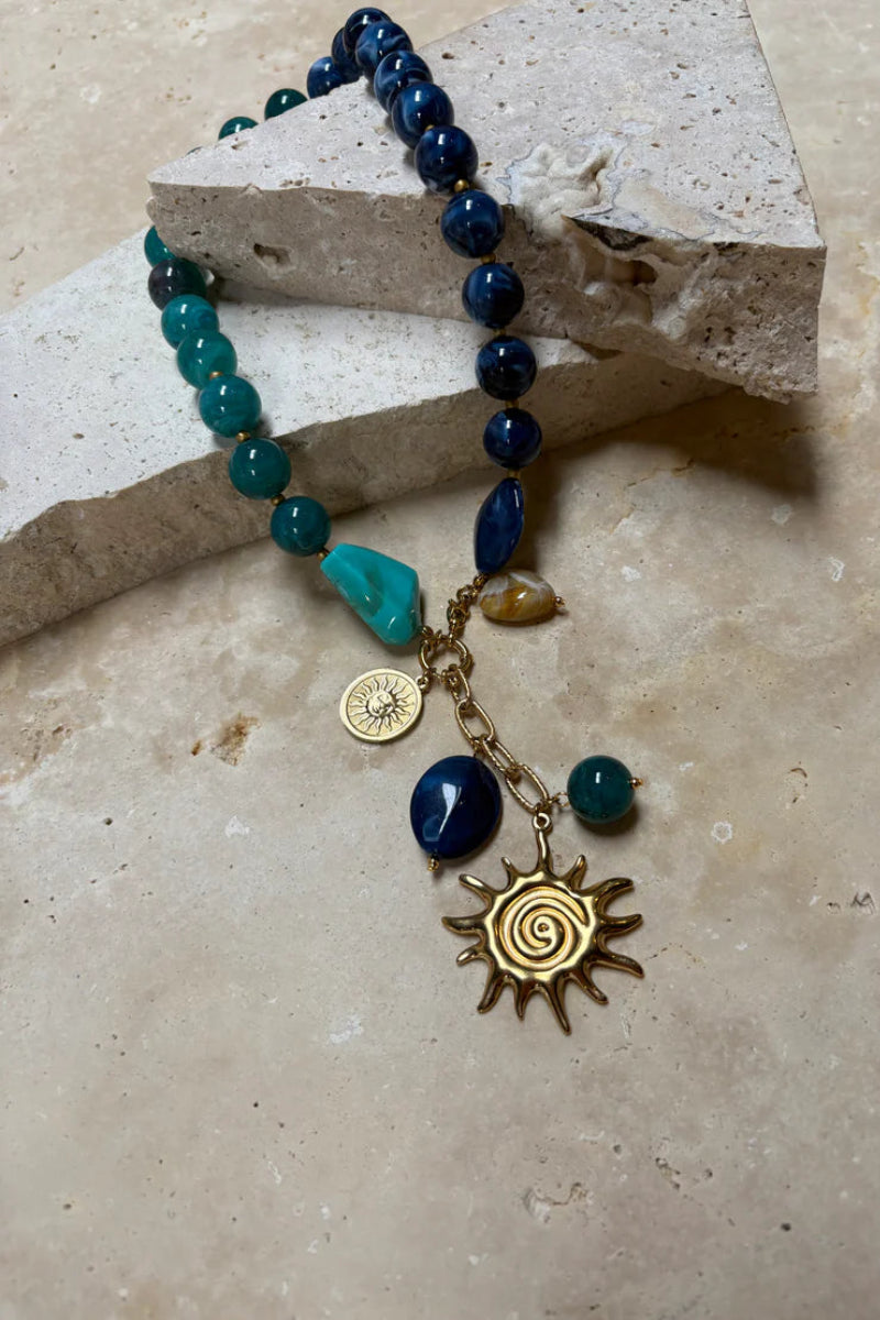 Beaded bracelet with sun charm on a stone surface