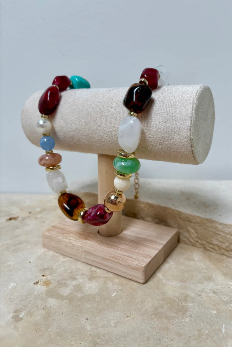 Colorful beaded bracelet on a wooden stand with a marble background