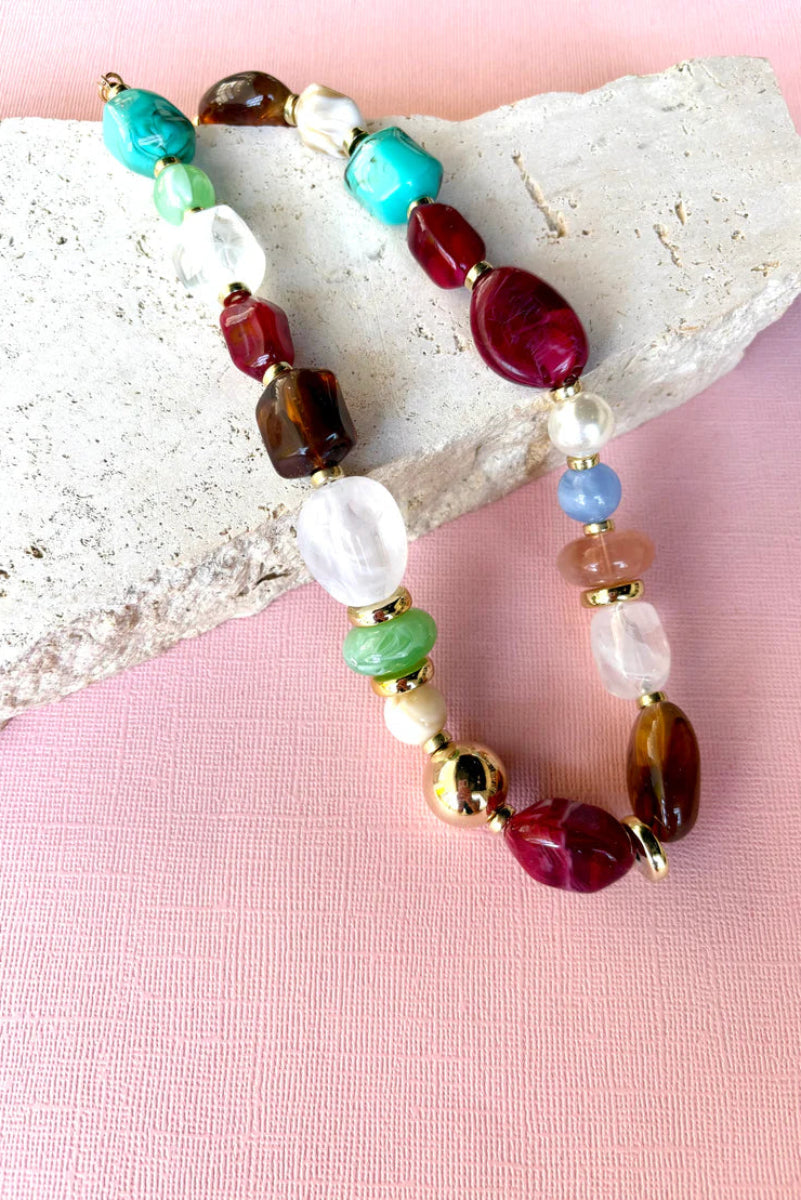 Colorful beaded bracelet on a stone with a pink background