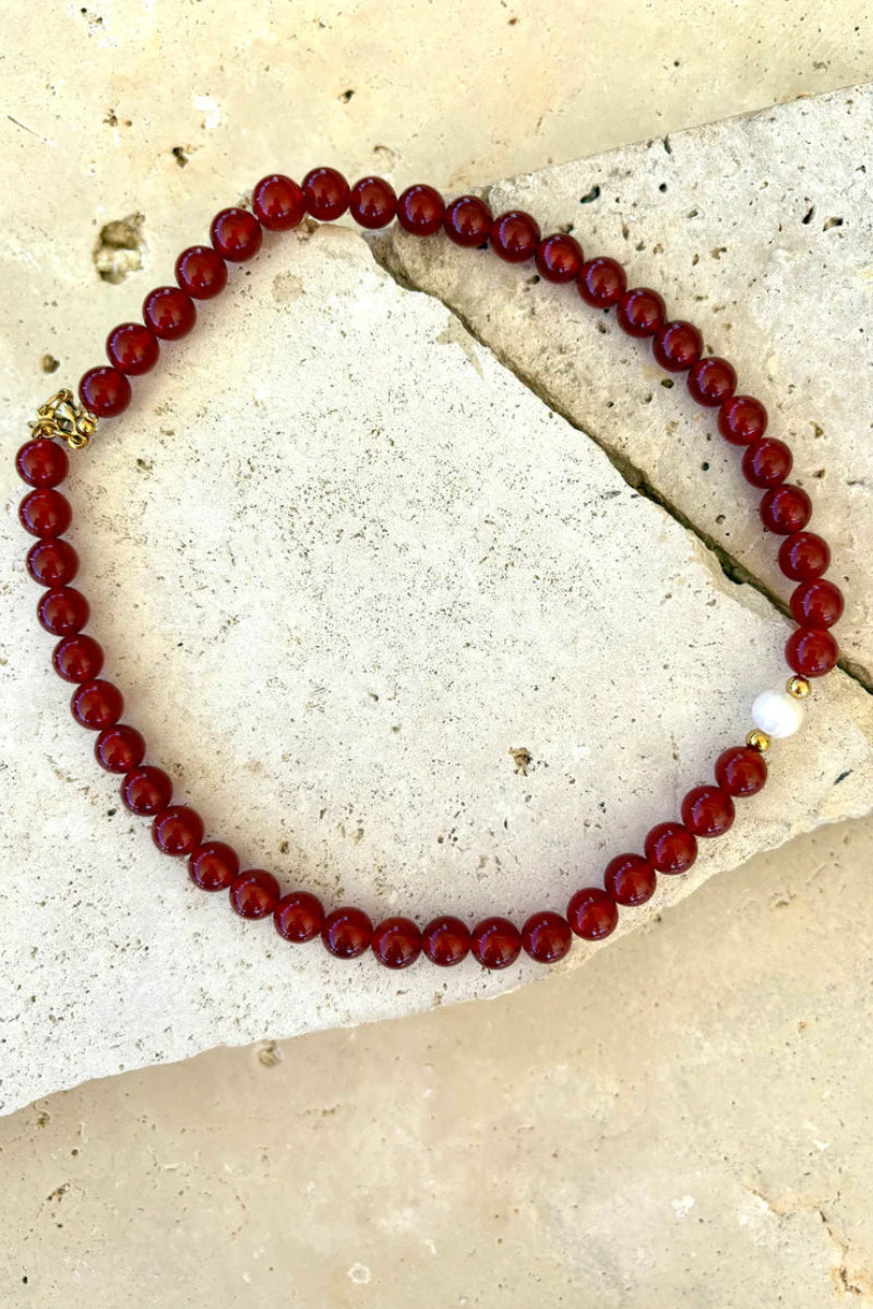 Red beaded bracelet on a textured stone surface