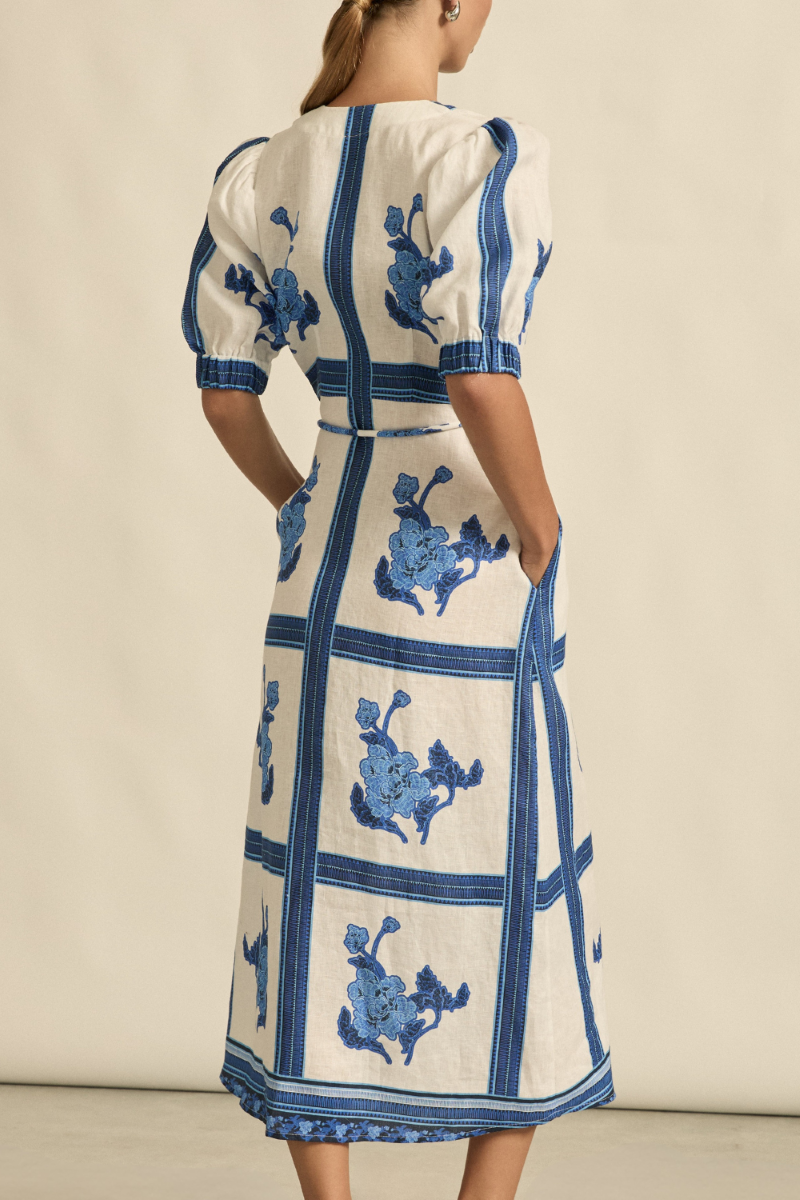 This back view of the Portrait Dress in Azure Collage showcases the gentle A-line shape, elasticated blouson sleeves, and clean linen fabric for a polished, effortless look.
