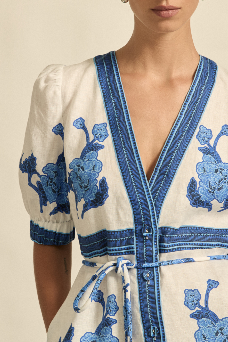 This close-up image of the Portrait Dress in Azure Collage captures the delicate covered buttons, textured linen fabric, and the fine details of the elasticated blouson sleeve.
