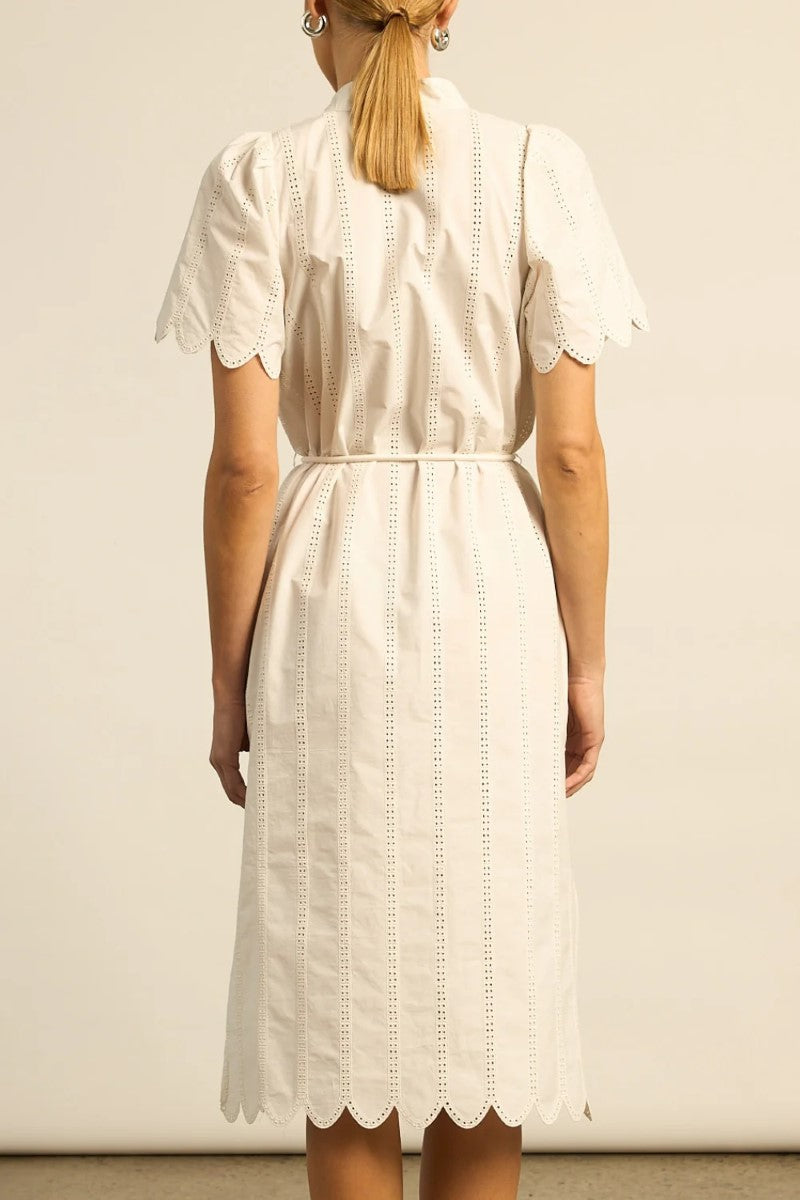 White dress with scalloped hem on a plain background