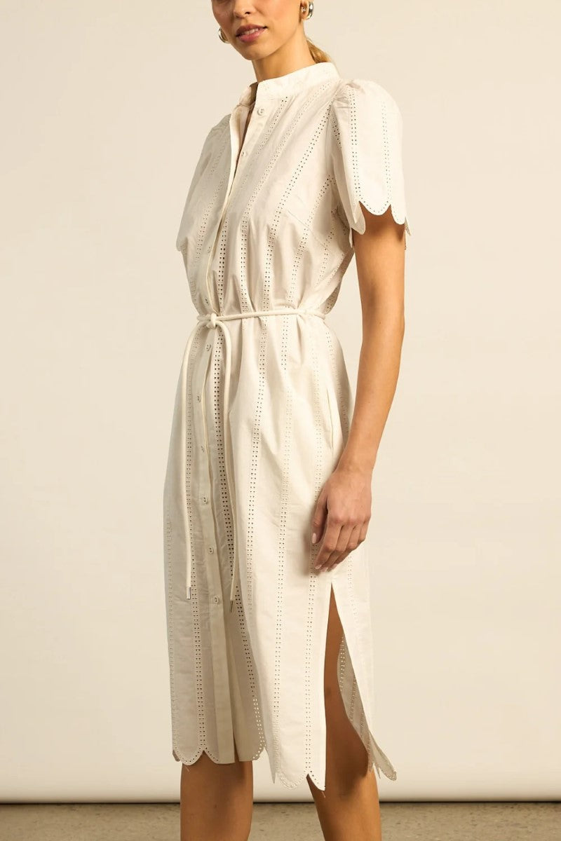 Woman wearing a white dress with a subtle pattern on a plain background