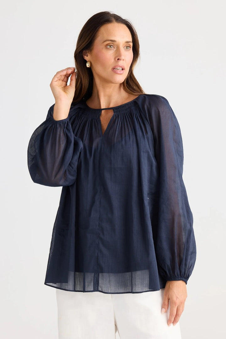 Woman wearing a navy blue blouse with long sleeves on a white background