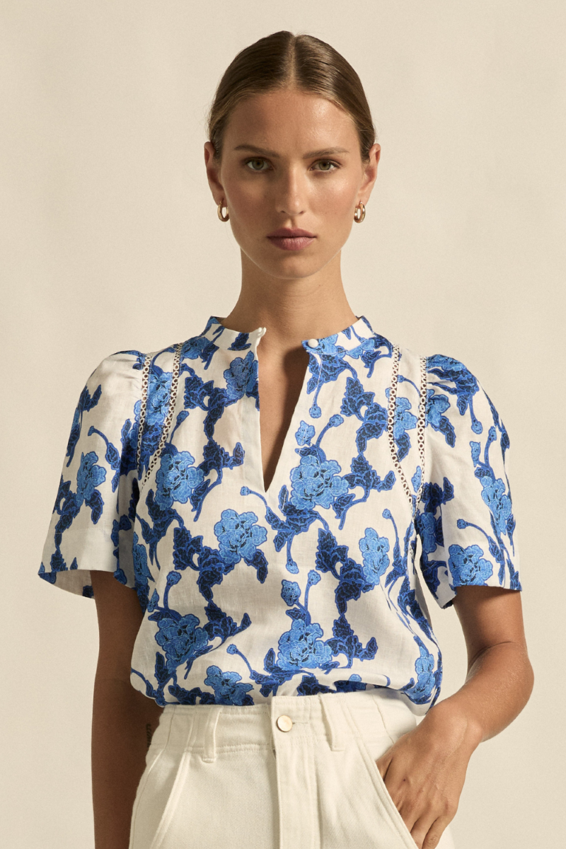 This front close-up image of the Recollect Top in Azure Bouquet highlights the delicate circular lace detailing on the shoulder, the covered dome button, and the textured 100% linen fabric.

