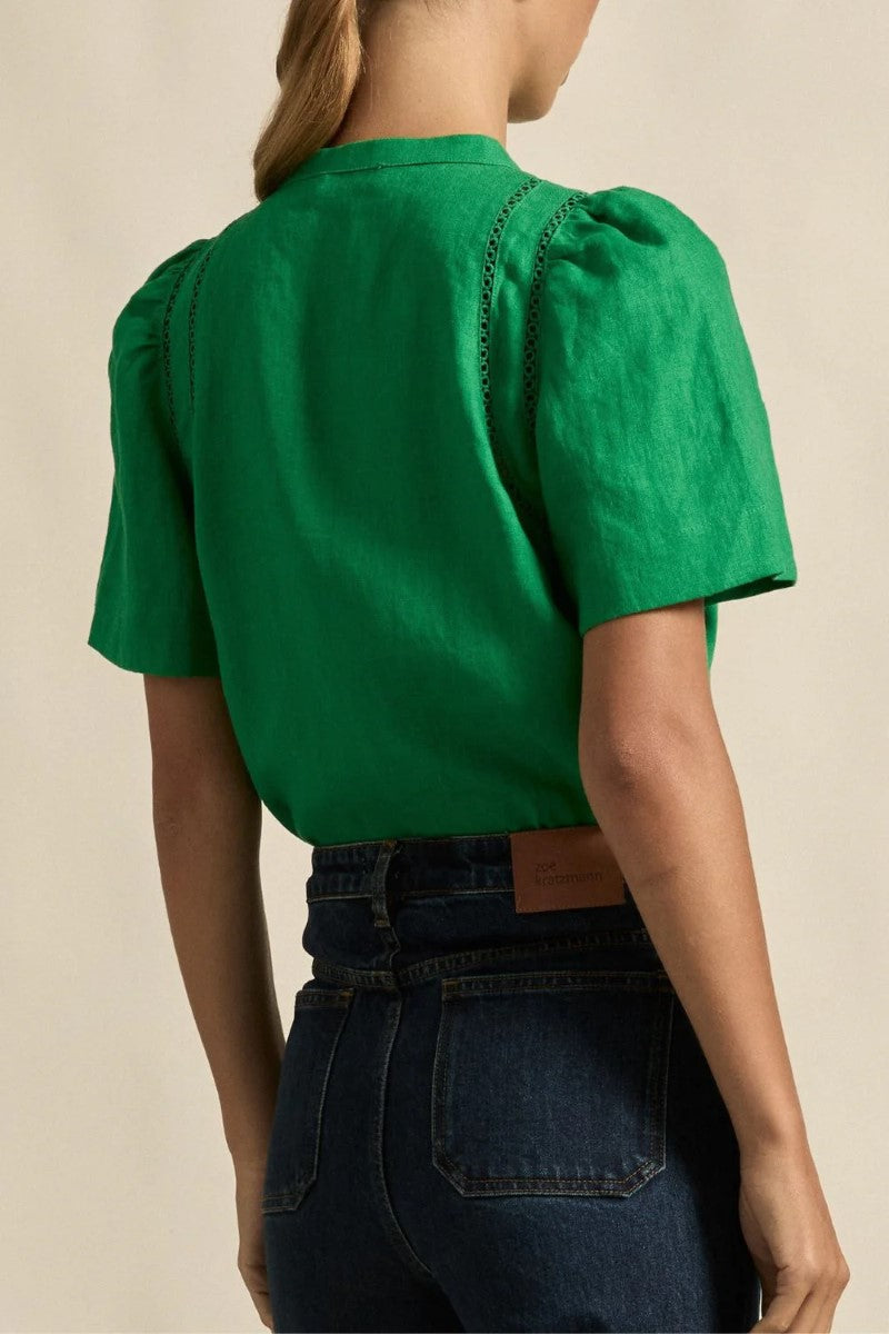 Green blouse with puffed sleeves worn by a person on a beige background
