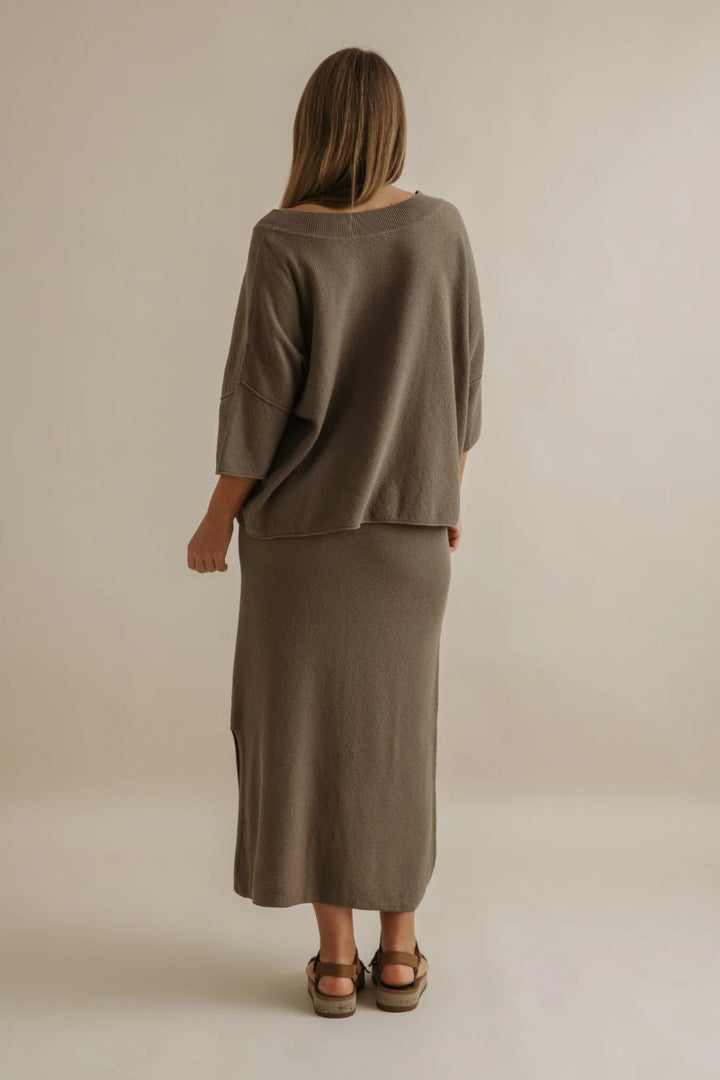 Person wearing a brown outfit standing against a plain background