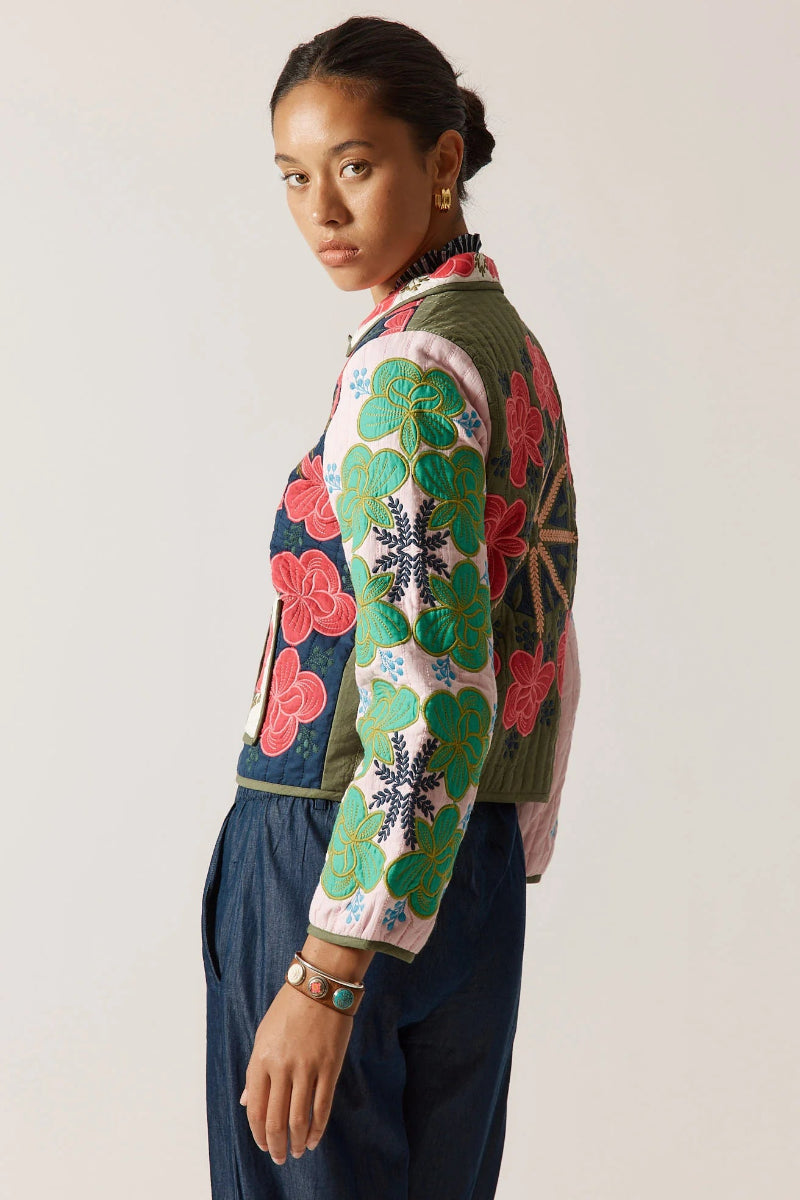 Woman wearing a colorful floral-patterned jacket against a plain background