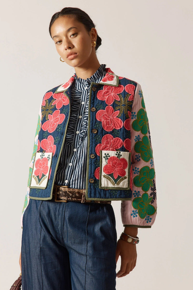 Person wearing a colorful floral jacket with a plain background