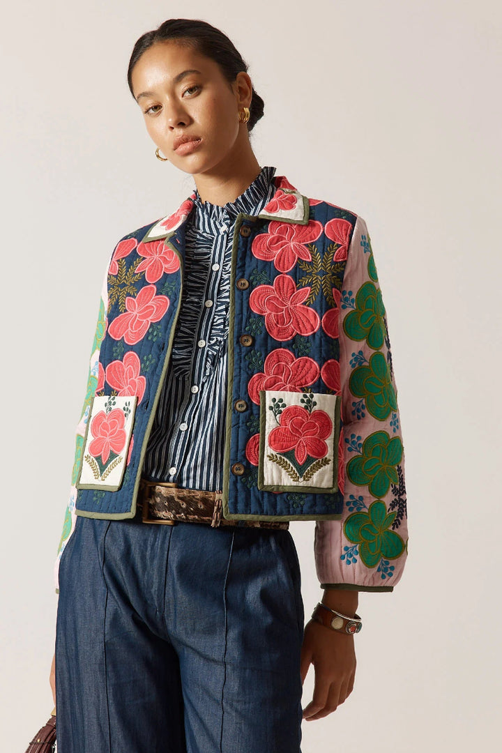 Person wearing a colorful floral jacket with a plain background