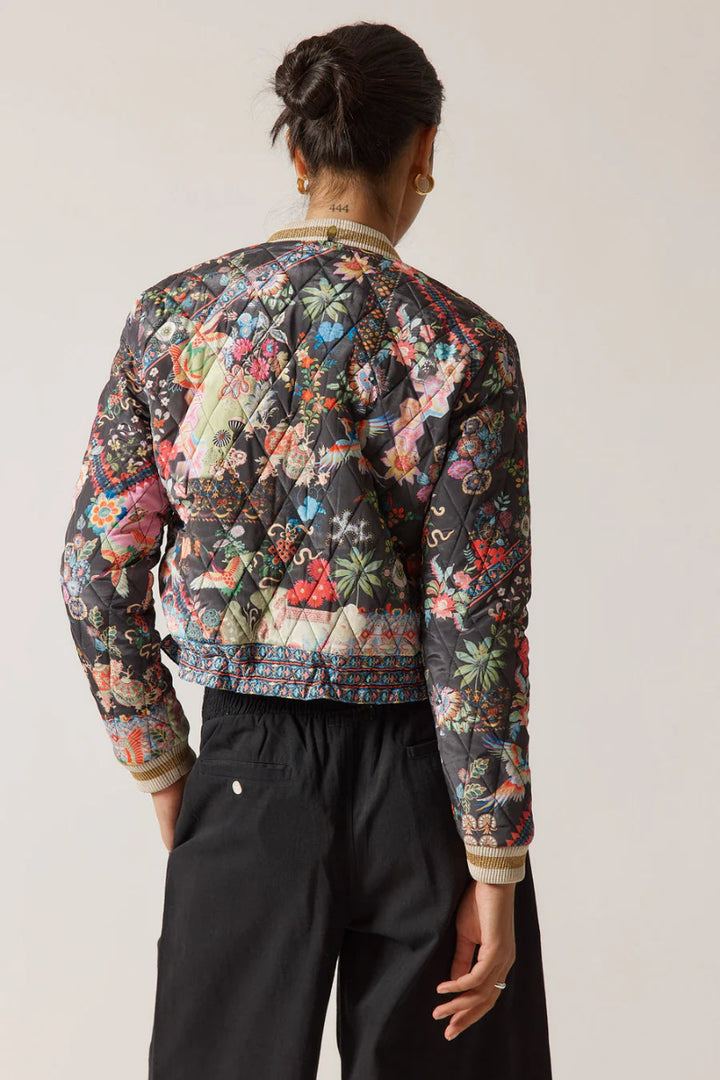 Person wearing a colorful floral-patterned jacket on a plain background