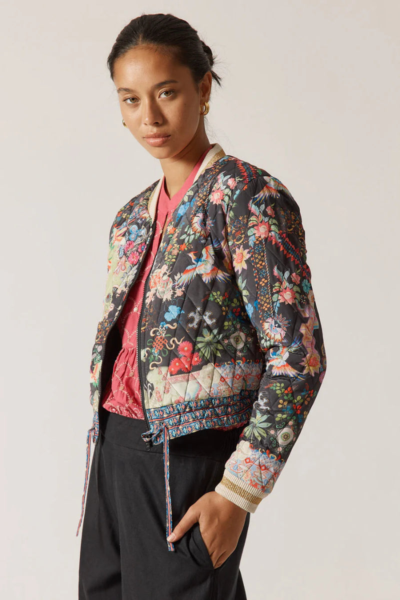 Woman wearing a colorful floral jacket on a plain background