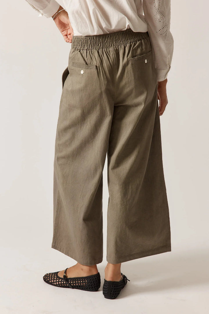 Person wearing olive green wide-leg pants on a plain background