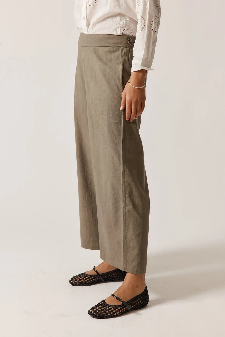 Person wearing beige wide-leg pants on a plain background