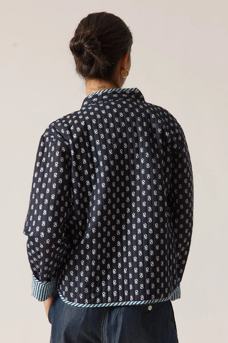 Person wearing a dark blue patterned shirt against a plain background