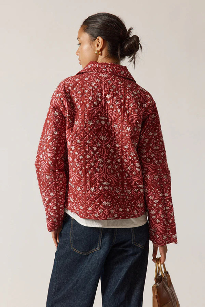 Person wearing a red floral jacket with a plain background