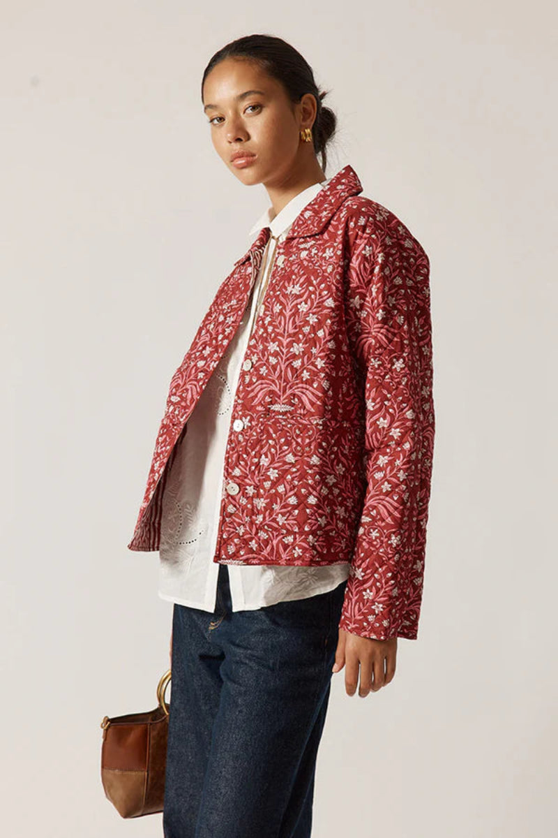 Person wearing a red patterned jacket on a plain background