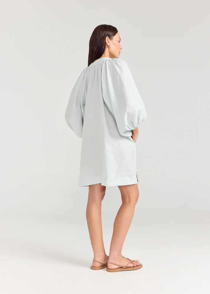 Woman wearing a light gray dress with puffed sleeves on a white background