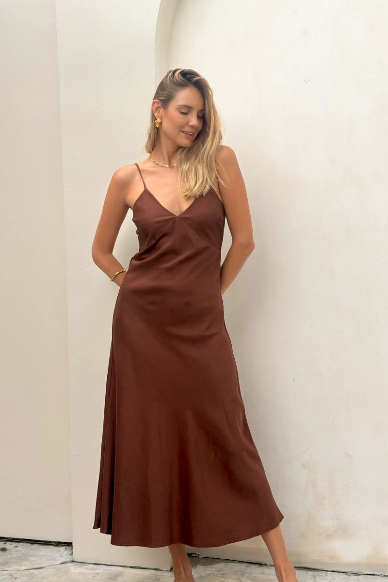 Woman wearing a brown slip dress against a white wall