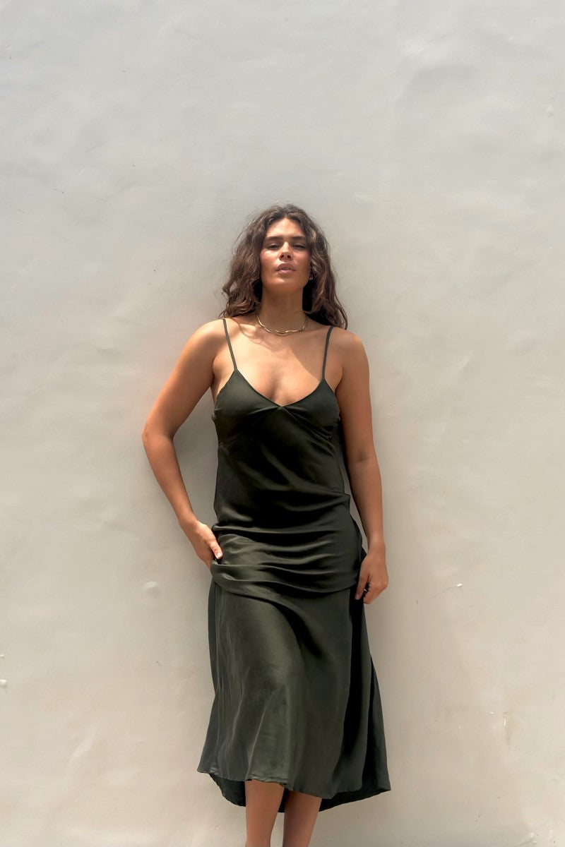 Woman wearing a green slip dress against a plain background