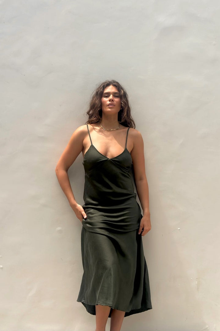 Woman wearing a green slip dress against a plain background
