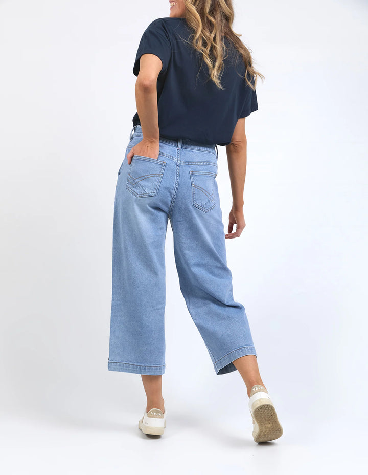 Person wearing a navy t-shirt and light blue jeans on a white background