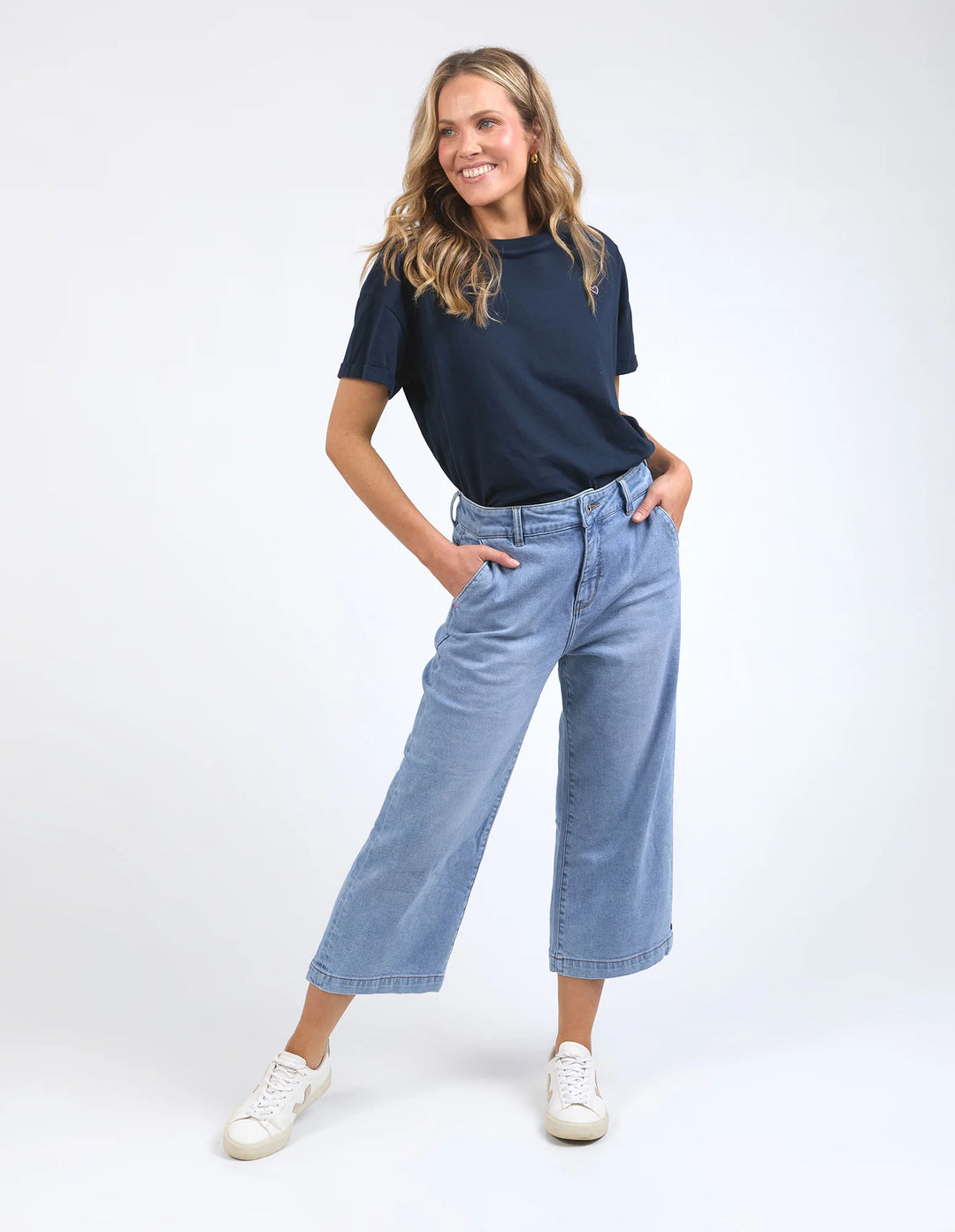 Woman wearing a navy t-shirt and light blue jeans on a white background