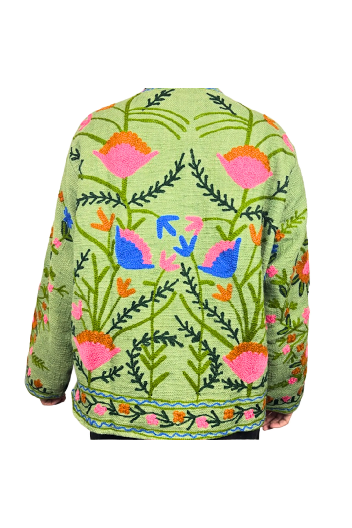 Green sweater with colorful floral and abstract designs on a white background
