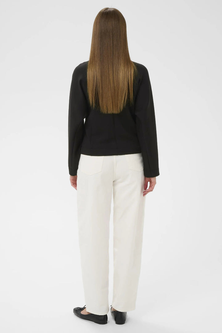 Person wearing a black blazer and white pants on a white background