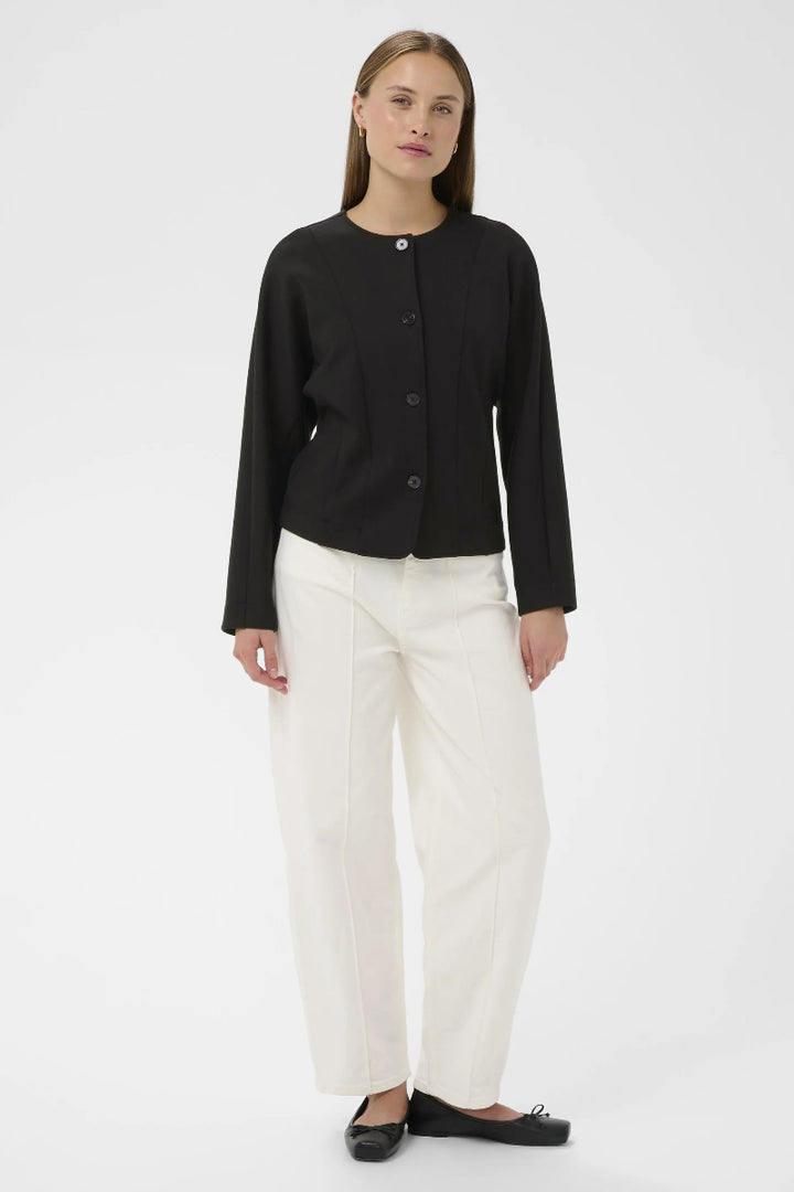 Woman wearing a black jacket and white pants on a white background