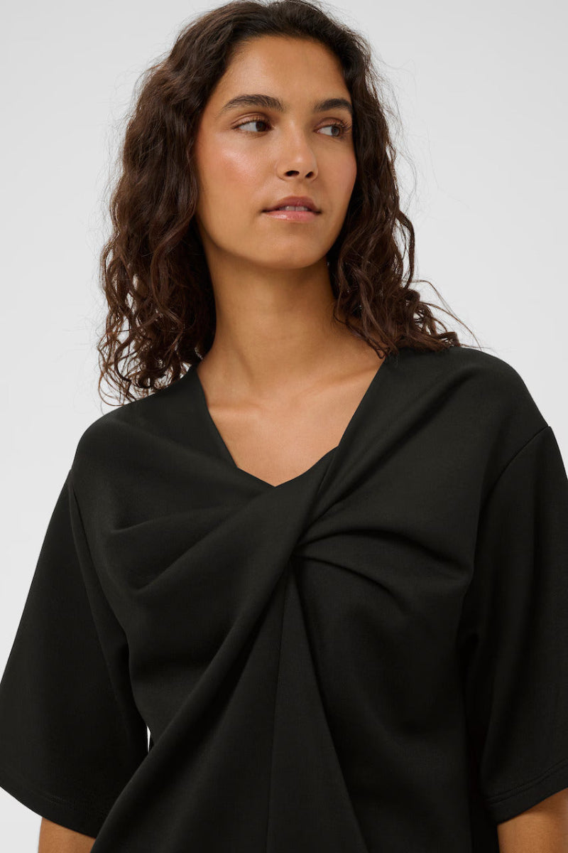 Woman wearing a black top with a knot detail on a white background