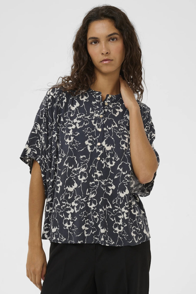 Woman wearing a black floral patterned blouse against a white background