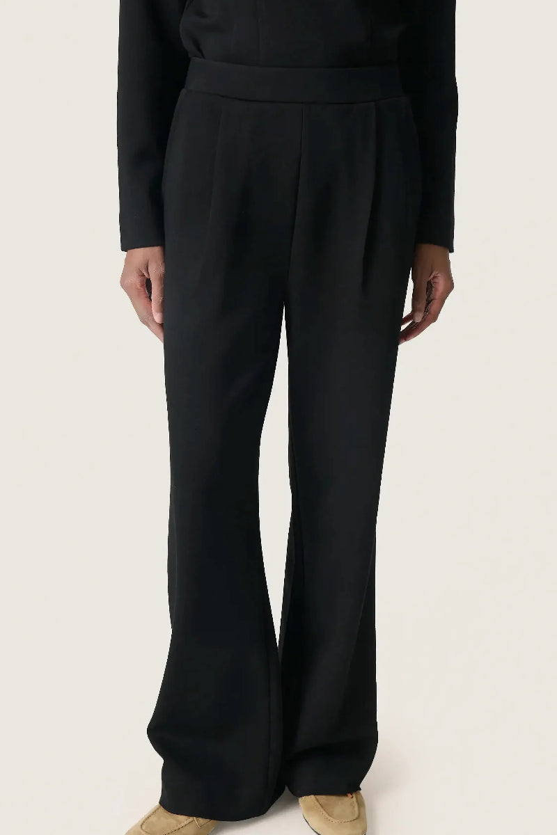 Person wearing black wide-leg pants on a white background