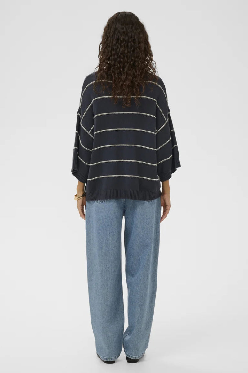 Person wearing a black and white striped sweater and light blue jeans on a white background
