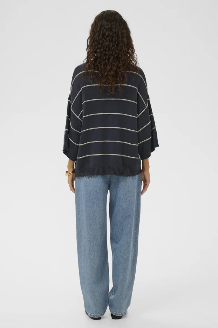 Person wearing a black and white striped sweater and light blue jeans on a white background