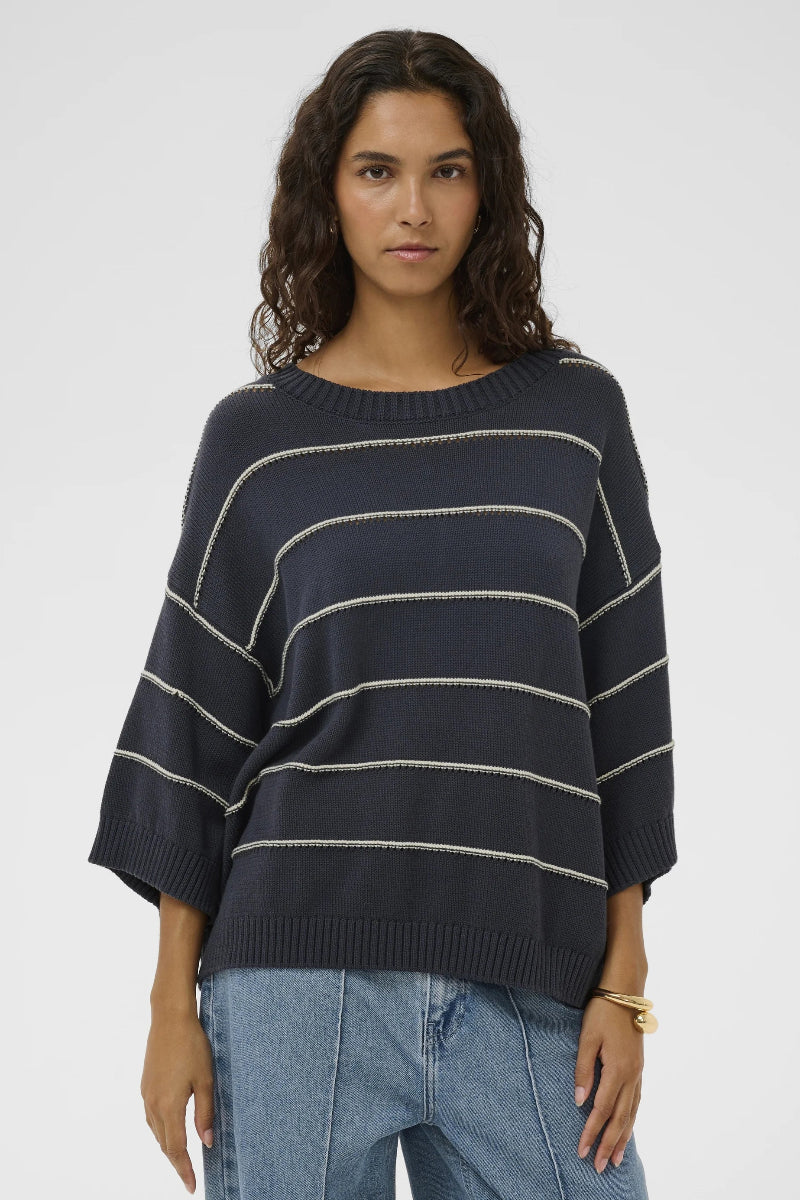 Woman wearing a navy striped sweater and jeans on a white background