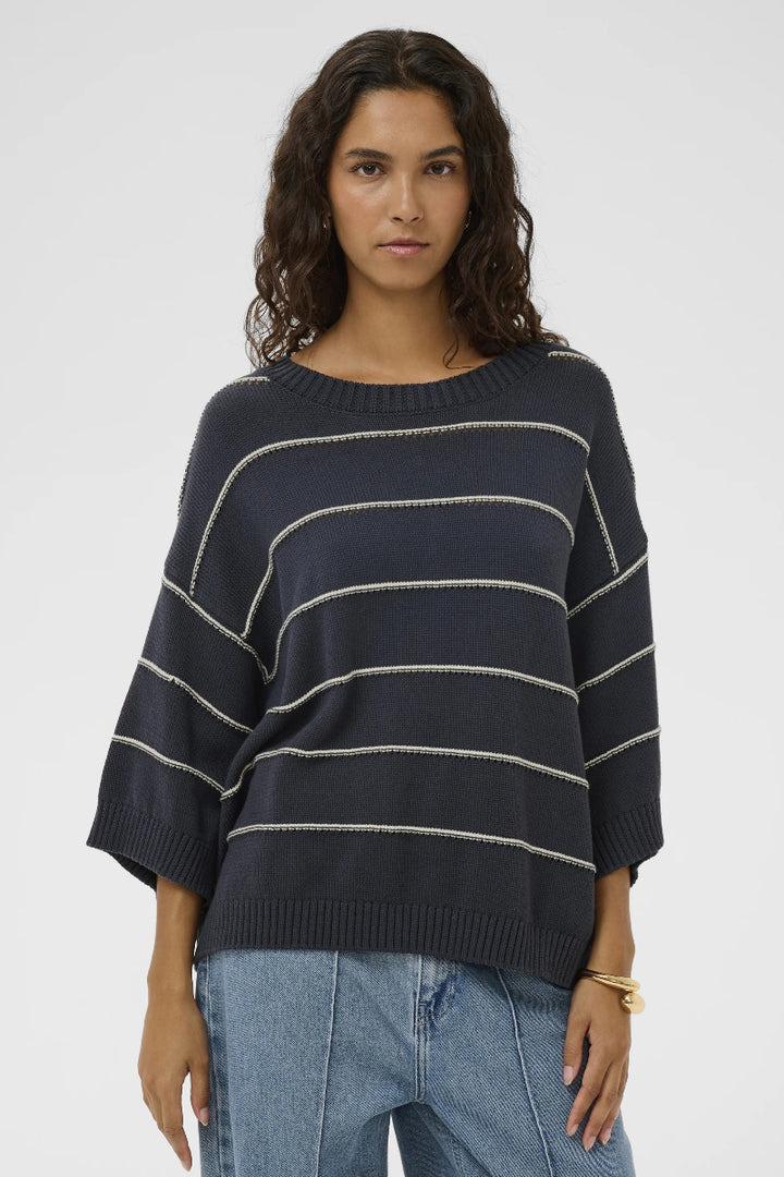 Woman wearing a navy striped sweater and jeans on a white background
