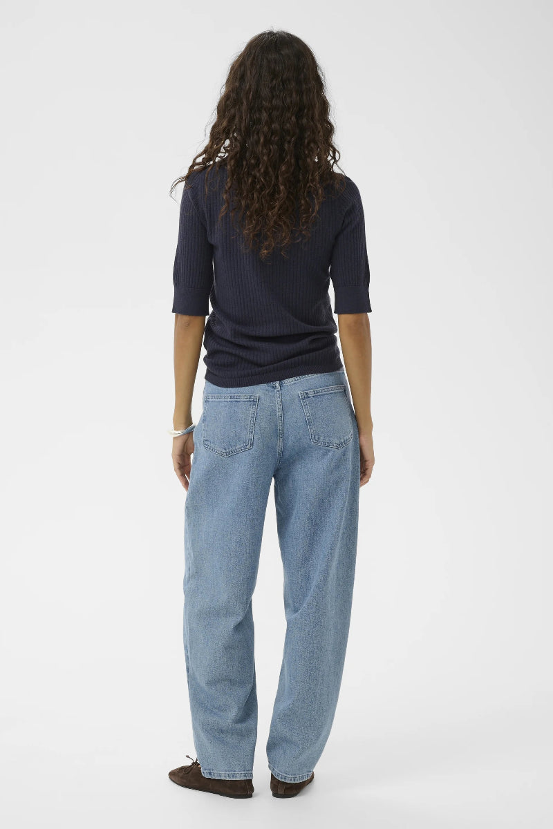 Person wearing a navy shirt and light blue jeans on a white background